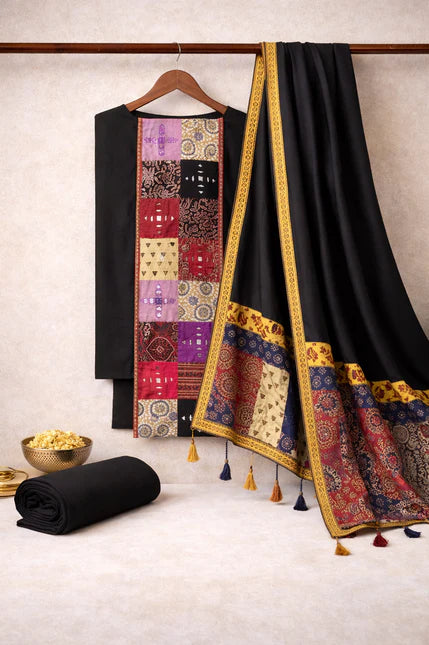 Black fabric with colorful patterns and tassels on a hanger against a neutral background