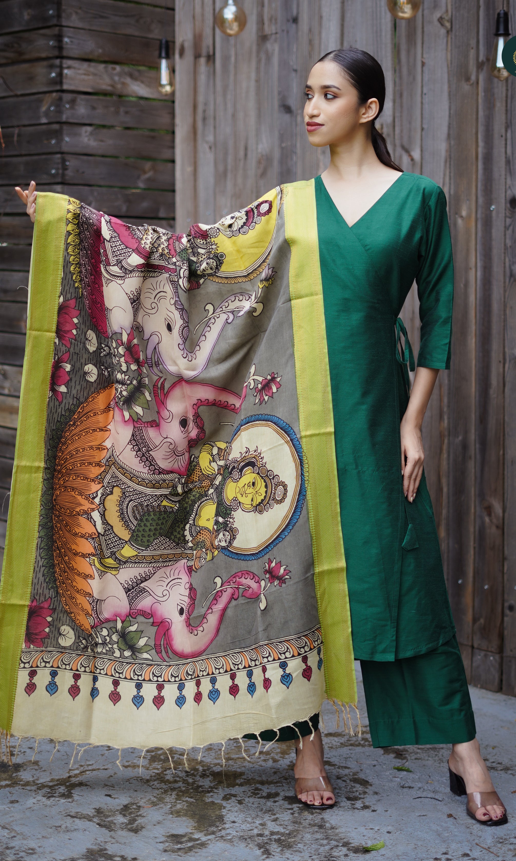A woman modeling an emerald green and Kalamkari suit set with a cotton silk kurta, tailored bottoms, and a Kalamkari dupatta featuring hand-painted patterns.