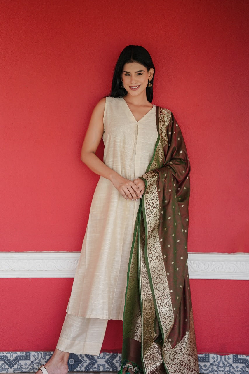 Woman in a white outfit with a brown and green patterned scarf against a red wall.