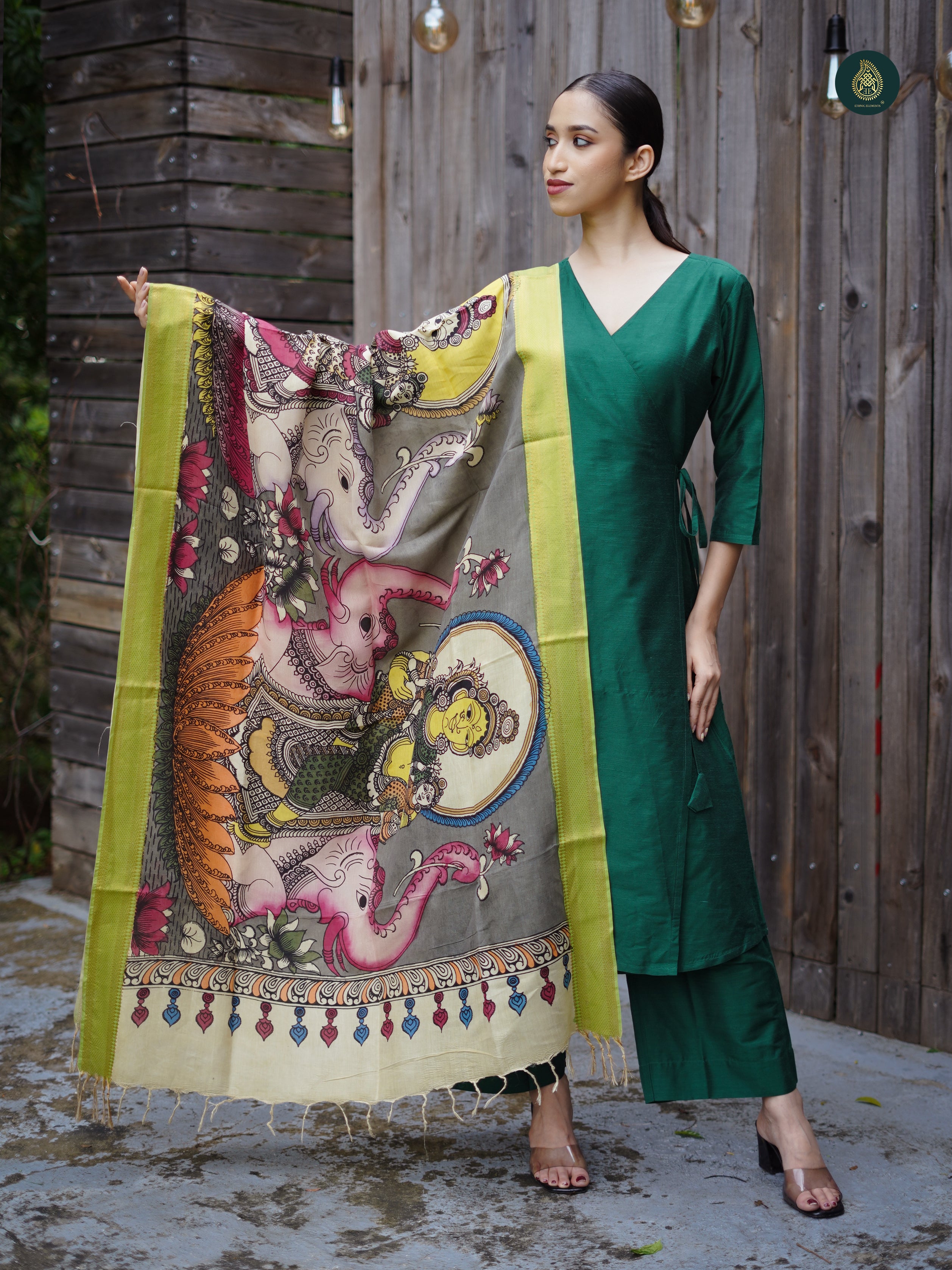 A woman modeling an emerald green and Kalamkari suit set with a cotton silk kurta, tailored bottoms, and a Kalamkari dupatta featuring hand-painted patterns.